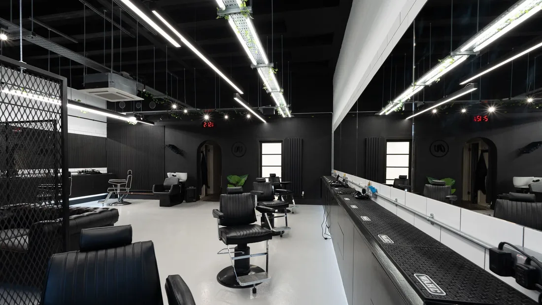 Inside Your Barber: barber's chairs along a lit mirror wall, black walls and ceiling.
