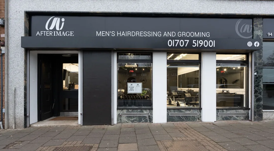 The front of Your Barber on Buckingham Palace - a black shopfront with the sign above the window and the phone number above the door.